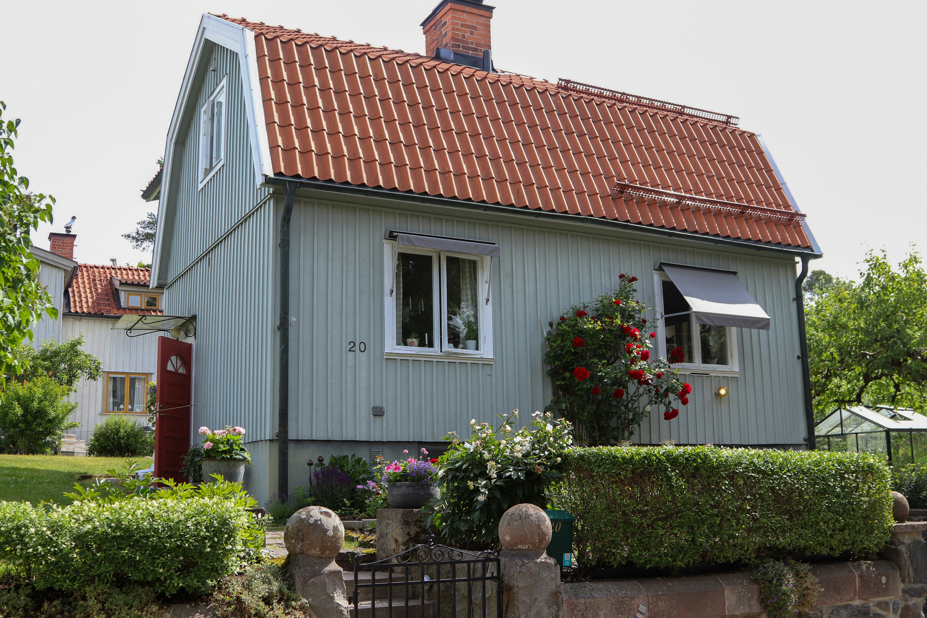 A charming, light-blue house with a red roof